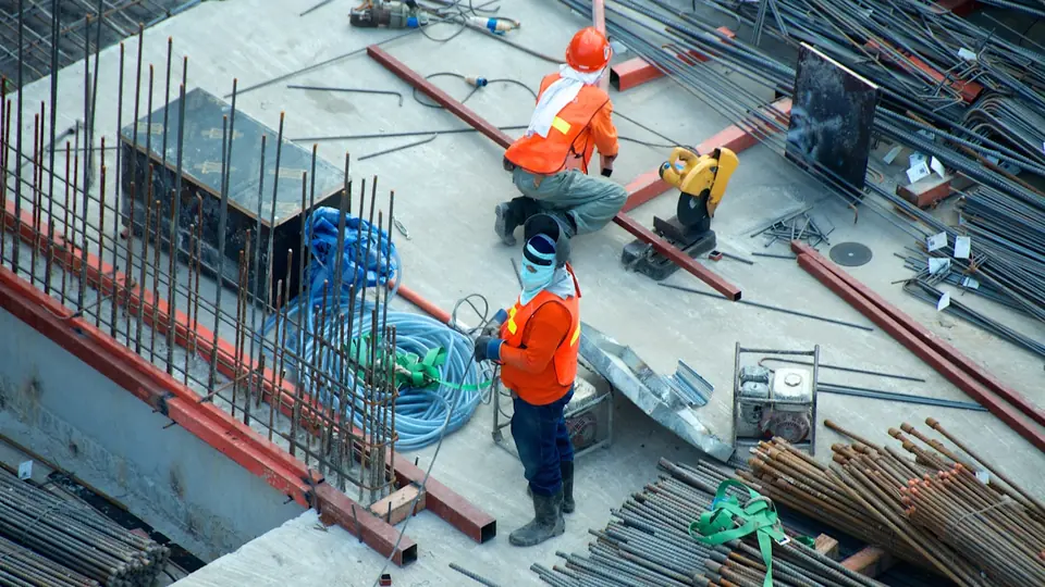 Large commercial construction site with heavy roll off dumpster containers and construction workers in hardhats